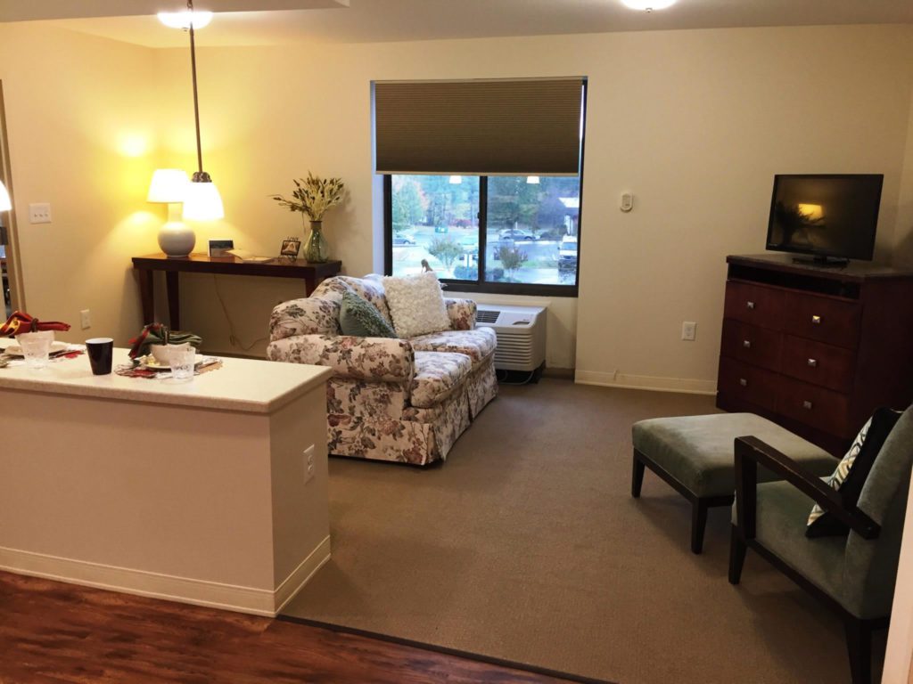 A living room with a couch, chair and television.