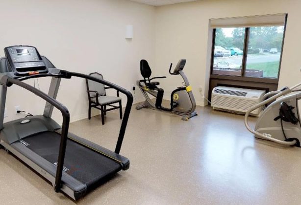 A room with two exercise machines and a treadmill.