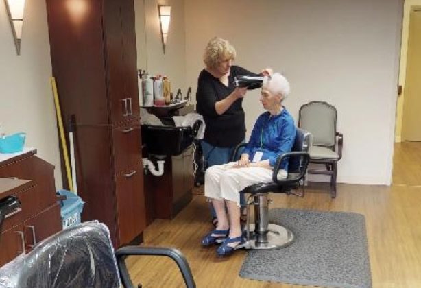 A woman is getting her hair cut by another person.