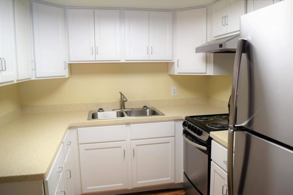 A kitchen with white cabinets and yellow walls.