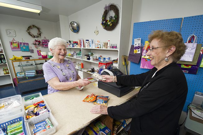 A woman is handing something to an older lady.