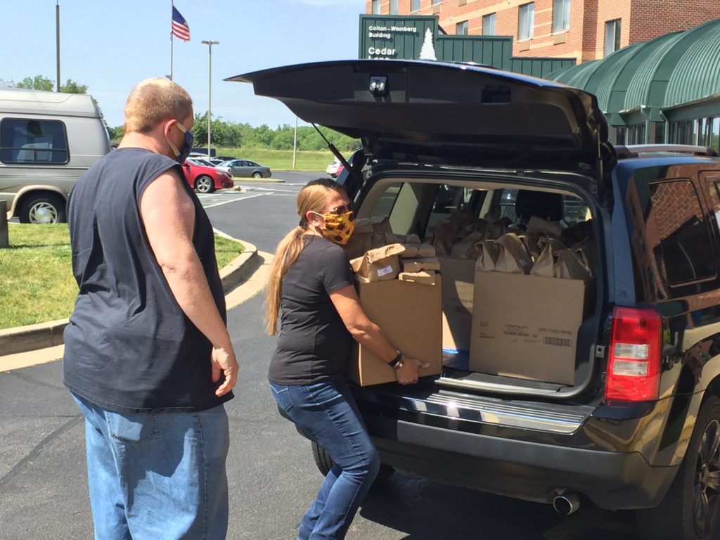 A woman loading boxes into the back of a car.