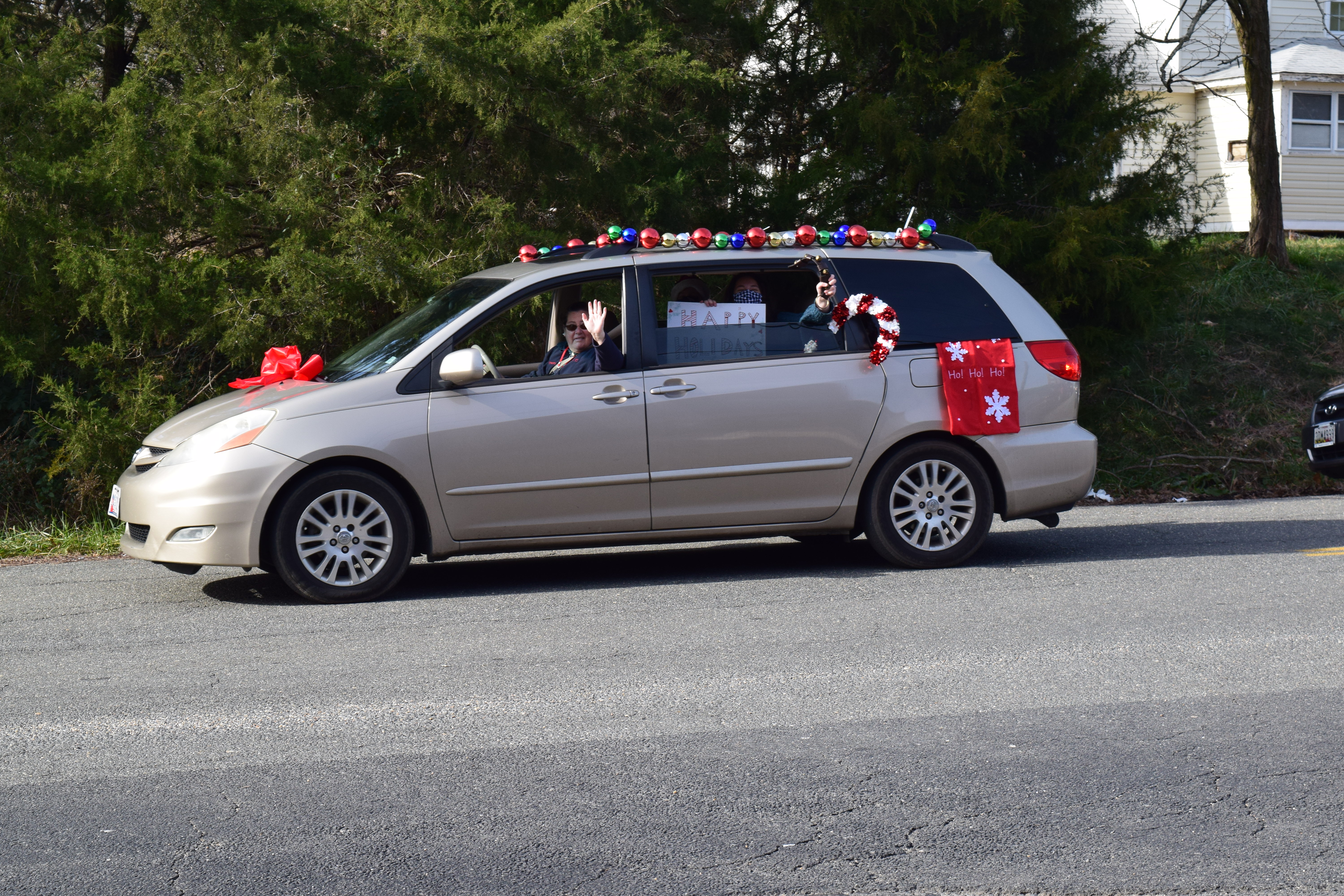 A van with christmas decorations on the roof drives down the street.