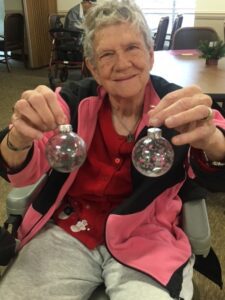 A woman holding two glass ornaments in her hands.