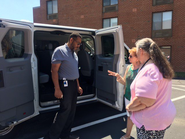 A man and woman standing next to an open van.