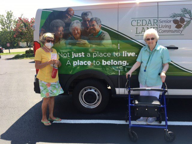 Two women standing next to a van with a sign on it.