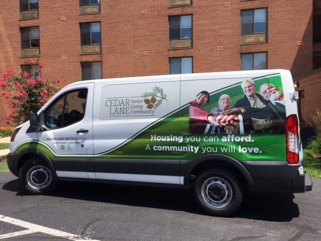 A van with a green and white wrap on the side of it.