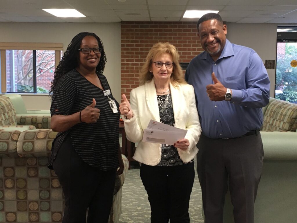 Three people giving thumbs up in a room.