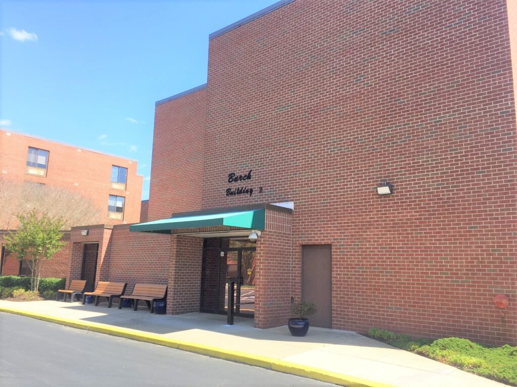 A brick building with a green awning and two benches.