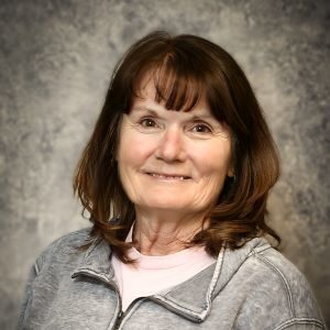 A woman with long hair and bangs is smiling.