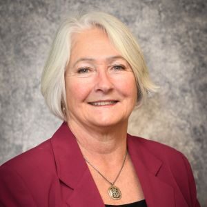 A woman with white hair wearing a red jacket.