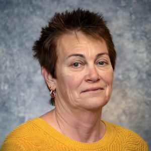 A woman with short hair wearing an orange sweater.