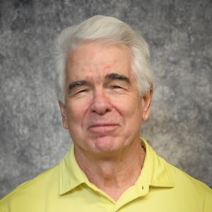 A man with white hair and a yellow shirt.