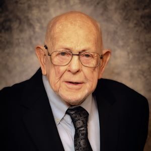 A man in glasses and a suit is smiling.