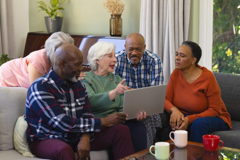 Group of people gathered around a laptop.